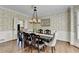 Elegant dining room with hardwood floors, patterned wallpaper, wainscoting, and a chandelier over a formal table at 865 Mount Katahdin Trl, Johns Creek, GA 30022