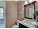 Powder room with a marble topped vanity, framed mirror and neutral wall color at 955 Bishopswood Pl, Johns Creek, GA 30022