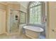 Bright bathroom featuring a standalone tub, glass shower, and marble accents at 955 Bishopswood Pl, Johns Creek, GA 30022