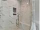 Luxurious walk-in shower featuring elegant marble tile, a convenient built-in seat, and modern fixtures at 955 Bishopswood Pl, Johns Creek, GA 30022