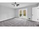 Bright bedroom featuring a ceiling fan, gray walls, gray carpet, and french doors that lead to a deck at 175 Montego Cir, Riverdale, GA 30274
