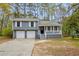 Charming split-level home with a two-car garage, covered porch, and gray siding nestled among mature trees at 175 Montego Cir, Riverdale, GA 30274