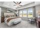 Spacious bedroom with tray ceilings, a ceiling fan, a sitting area, and large windows allowing natural light at 522 Provence Gate Ln, Lawrenceville, GA 30044