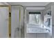 Bathroom featuring a jacuzzi tub, seamless glass shower, and a large window with natural light at 5717 Harmony Point Dr, Lilburn, GA 30047