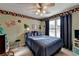 A bedroom with a sports theme, featuring a ceiling fan, a window with blinds, and carpet at 5717 Harmony Point Dr, Lilburn, GA 30047