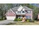 Beautiful two-story brick home with a manicured lawn, front porch, and attached two-car garage at 5717 Harmony Point Dr, Lilburn, GA 30047