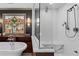 Bright bathroom featuring a soaking tub, glass shower and decorative window at 1890 Spalding Dr, Atlanta, GA 30350