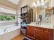 Relaxing bathroom featuring a soaking tub, dark wood cabinets, and a large mirror at 4030 Gold Mill Rdg, Canton, GA 30114