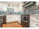 Close-up of kitchen features stainless steel oven, white cabinets, and eye-catching backsplash at 708 Mcgill Ne Pl, Atlanta, GA 30312