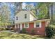 Charming two-story home features a brick facade, light yellow siding, and a covered carport in a lush, green setting at 3052 Sw Highbury Sw Trl, Atlanta, GA 30354