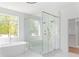 Luxurious bathroom with a large glass shower, marble tile, soaking tub, and natural light at 504 Barrington Dr, Roswell, GA 30075