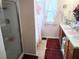 Bright bathroom with a glass door shower, double sink vanity, and decorative pink curtains over the window at 1074 Deshon Trl, Lithonia, GA 30058