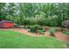 Lush backyard featuring a well-maintained lawn, beautiful landscaping, a wooden fence, and a storage shed at 29 Fern Leaf Ct, Dallas, GA 30157