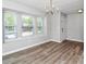 Bright dining room featuring stylish chandelier, wood flooring, and large windows at 5477 Hedgeflower Ct, Stone Mountain, GA 30088