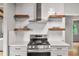 Well-appointed kitchen featuring floating shelves, stainless steel appliances, quartz countertops and a modern vent hood at 3185 Laventure Dr, Chamblee, GA 30341