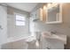 Clean bathroom with white tile, shower-tub combo, white vanity, matching medicine cabinet and updated fixtures at 1019 Magbee Se Dr, Smyrna, GA 30080