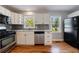 Updated kitchen features white cabinets, stainless steel appliances, gray tile backsplash and hardwood flooring at 1019 Magbee Se Dr, Smyrna, GA 30080