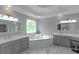 Bright bathroom featuring double sinks, soaking tub, and a decorative leaded-glass window at 3510 Donegal Way, Snellville, GA 30039