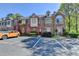 Townhome with brick and stone facade, red door, manicured shrubs, and visitor parking spaces at 1213 Harris Commons Place, Roswell, GA 30076