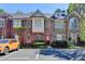 Townhome with brick and stone facade, red door, manicured shrubs, and visitor parking spaces at 1213 Harris Commons Place, Roswell, GA 30076