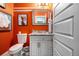 Charming powder room featuring bright orange walls, gray vanity and decorative mirror at 3308 Pate Rd, Snellville, GA 30078