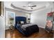 Stylish bedroom with a blue tufted headboard, tray ceiling, and hardwood floors at 3308 Pate Rd, Snellville, GA 30078