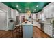 Modern kitchen features stainless steel appliances, white cabinets, a green ceiling, and an island with bar seating at 3308 Pate Rd, Snellville, GA 30078