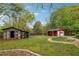 View of the backyard featuring a red shed, a weathered shed, and a stone-lined garden on a sunny day at 4290 Chestnut Grove Ln, Austell, GA 30106