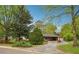 The brick home features a covered parking, a beautiful lawn, and landscaping, all framed by mature trees and a scenic road at 4290 Chestnut Grove Ln, Austell, GA 30106