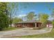 This brick home features covered parking, landscaping, a spacious driveway, and red garage, all set amidst mature trees at 4290 Chestnut Grove Ln, Austell, GA 30106