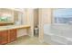 Bright bathroom featuring a soaking tub, vanity, neutral paint, separate toilet room, and natural light at 3642 Sunbridge Dr, Snellville, GA 30039