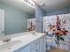 Bright bathroom featuring double sinks, large mirror, floral shower curtain, and updated fixtures at 111 Riverstone Commons Cir, Canton, GA 30114