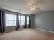 Spacious bedroom featuring neutral carpet, three large windows, and a ceiling fan at 111 Riverstone Commons Cir, Canton, GA 30114