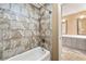 Neutral tiled bathroom with a shower-tub combo and an elegant double sink vanity with large mirror at 1460 Edgemont Pt, Lawrenceville, GA 30044