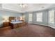 Spacious main bedroom featuring a tray ceiling, ceiling fan, light blue walls and a rustic wooden bed set at 1460 Edgemont Pt, Lawrenceville, GA 30044