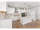 Stylish kitchen features white cabinetry, herringbone backsplash, stainless appliances, and large center island at 3681 Deaton Trl, Buford, GA 30519
