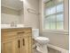 Bright bathroom features a wooden vanity, toilet, and window with privacy glass at 7535 Asbury Dr, Riverdale, GA 30274