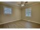 Empty bedroom has modern flooring, neutral paint, two windows, and a ceiling fan at 7535 Asbury Dr, Riverdale, GA 30274