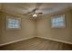 Bright bedroom with modern flooring, a ceiling fan, two windows, and neutral paint at 7535 Asbury Dr, Riverdale, GA 30274