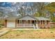 Inviting brick home with a covered porch, complemented by the natural landscape at 7535 Asbury Dr, Riverdale, GA 30274