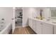 Bright bathroom featuring double vanity, white cabinets, wood-look flooring, and a tub, offering a serene and modern feel at 4504 Ajo Lot#2 Walk, Atlanta, GA 30331