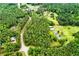 Lush aerial view of a country home surrounded by dense forest with a curving driveway and multiple outbuildings at 3545 Liberty Rd, Villa Rica, GA 30180