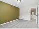 Inviting bedroom with neutral carpet, olive accent wall, and a glimpse of the hallway at 8355 Ainsworth Dr, Cumming, GA 30041