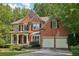 Charming brick home with a welcoming front porch and a two-car garage nestled among mature trees at 8355 Ainsworth Dr, Cumming, GA 30041