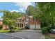 Classic brick home with a well-manicured lawn, covered porch, and attached two-car garage surrounded by trees at 8355 Ainsworth Dr, Cumming, GA 30041