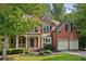 Charming brick home with a welcoming front porch and a two-car garage nestled among mature trees at 8355 Ainsworth Dr, Cumming, GA 30041