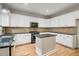 Bright kitchen offers granite countertops, a center island, and white cabinetry with a designer backsplash at 8355 Ainsworth Dr, Cumming, GA 30041