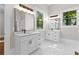 Bright bathroom featuring dual vanities, white cabinets, modern fixtures and white floors at 159 Forest Ave, Social Circle, GA 30025
