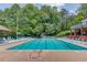 Large community swimming pool with lounge chairs and umbrellas surrounded by mature trees at 275 Sageglen Rd, Lawrenceville, GA 30044