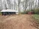 Cozy single-story home featuring a metal roof and a spacious dirt front yard with mature trees and a red storage shed at 110 N River Rd, Mcdonough, GA 30252